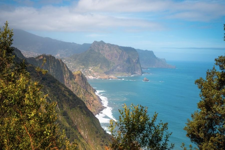 Layers of Madeira headlands running into the haze above a deep blue Atlantic, with houses scattered across the green slopes below
