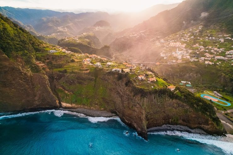 Aerial view of a cliffside village and terraced slopes above the Atlantic in Madeira