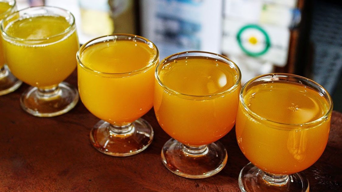 Glasses of poncha lined up on a wooden counter at a stall at the Poncha and Honey Festival.