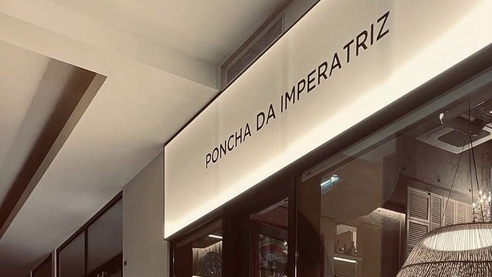 The lit Poncha da Imperatriz sign above the bar's glass front in the Gallerias arcade in Funchal