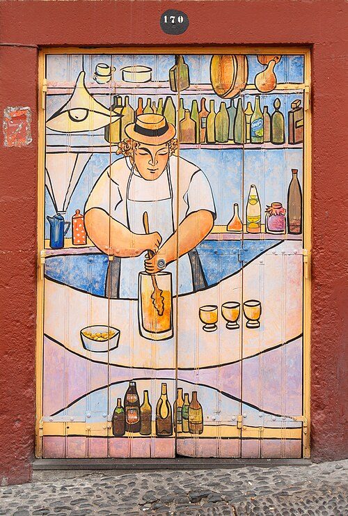 Painted door in Funchal showing a barman in a straw hat stirring poncha in a jug with a mexelhote, a bowl of dentinho beside him